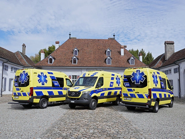 Drei Rettungswagen des Rettungsdienstes stehen auf historischem Hofplatz vor einem Gebäude, moderne Einsatzfahrzeuge in der Schweiz.