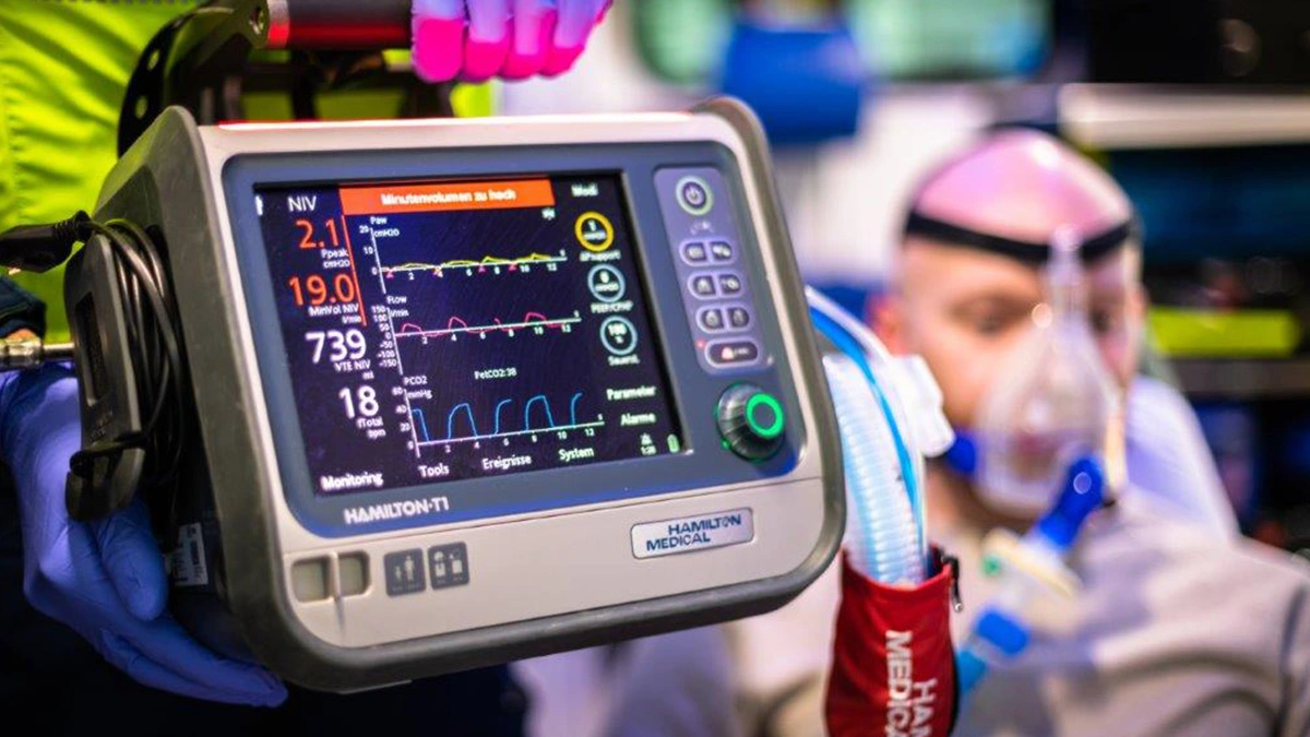 Rettungssanitäter nutzt Beatmungsgerät zur Überwachung eines Patienten mit Sauerstoffmaske im Rettungswagen während eines Notfalleinsatzes.