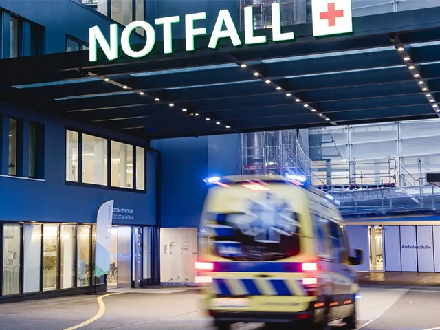 Rettungswagen fährt mit Blaulicht in die Notaufnahme eines Schweizer Spitals ein, schneller Einsatz im medizinischen Notfall.