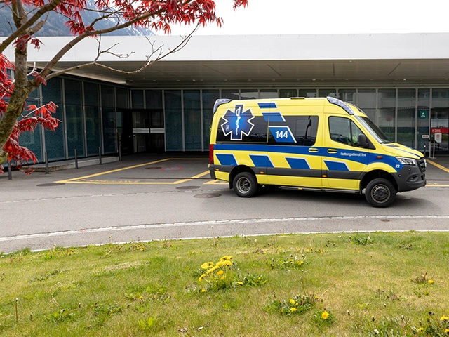 Rettungswagen steht vor Eingang eines Schweizer Spitals, bereit für Notfalleinsatz und Patiententransport durch den Rettungsdienst.