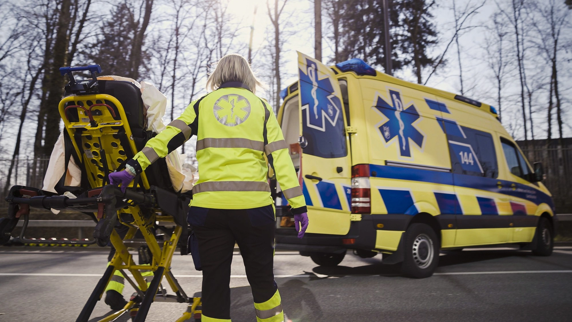 Rettungssanitäterin lädt Trage in Rettungswagen bei Tageslicht, Einsatz des Rettungsdienstes auf offener Strasse